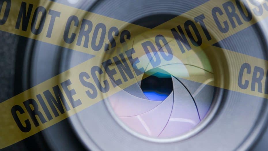 A camera aperture behind yellow crime scene tape - Pinnacle Forensics
